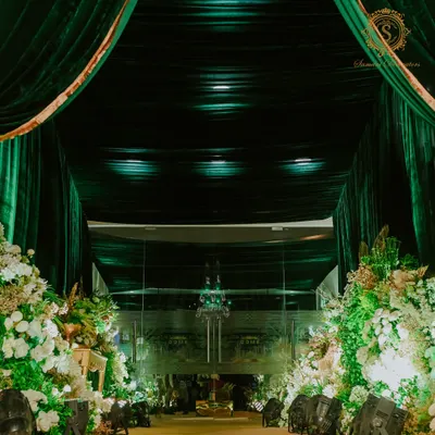 The entrance was a grand statement of emerald velvet. I created a tunnel of rich green fabric, leading guests through a path lined with opulent white and gold floral arrangements, setting a tone of pure luxury.