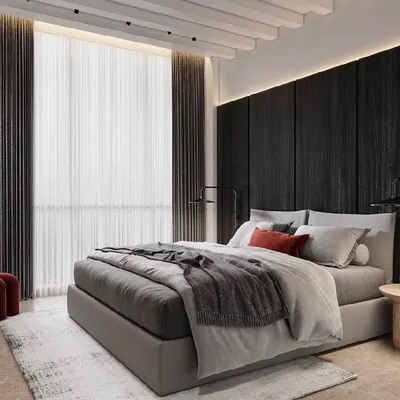 A dark and moody bedroom design. The black wood-paneled feature wall creates a dramatic and cozy backdrop, while the sculptural red chair adds a vibrant pop of color and artistic flair.