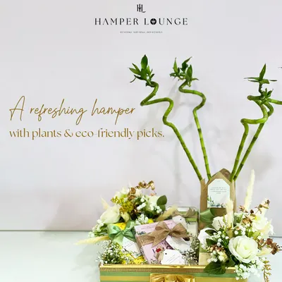 This is my signature refreshing hamper, featuring lucky bamboo stalks and eco-friendly picks. The items are arranged in a green and gold striped tray, adorned with white roses and other natural elements for a fresh, vibrant look.