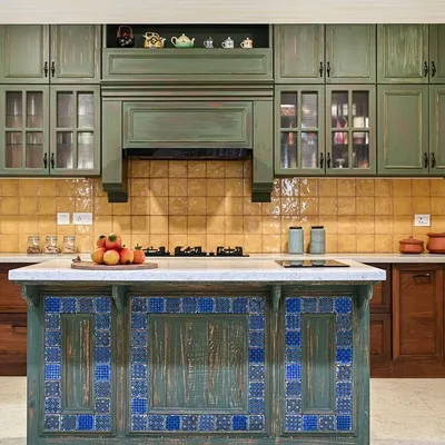 This kitchen is inspired by traditional architecture, with a symmetrical layout and a central island. The distressed olive green shutters, handmade yellow tiles, and vibrant Goan colors create a space full of character and charm.