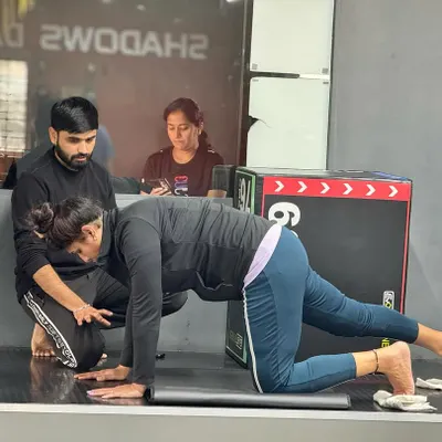 A trainer provides hands on guidance to a client during a core strengthening exercise, ensuring proper alignment and muscle engagement.