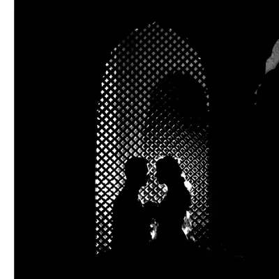 A stunning black and white silhouette of the couple against a latticed window. This artistic shot focuses on their form and connection, creating a timeless and romantic image.