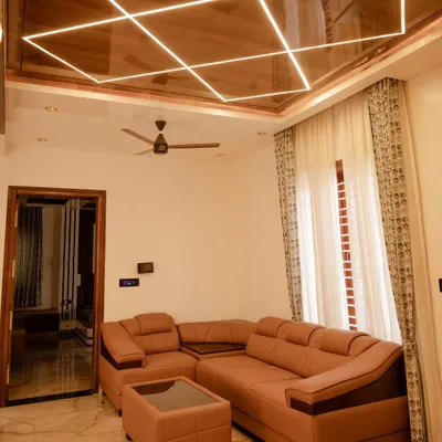 This living room features custom profile lighting integrated into a wooden ceiling panel. The geometric design creates a stunning visual centerpiece, while the automated curtains provide functional light control.