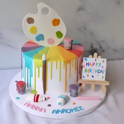 Bringing a splash of color to the birthday canvas. This artist-themed cake features a rainbow drip, an edible paint palette, brushes, and an easel.