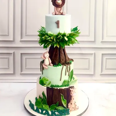 A three-tiered jungle adventure for a first birthday. This cake features a hand-sculpted tree trunk, lush sugar leaves, and adorable fondant animals like a lion, monkey, and giraffe, creating a wild and wonderful centerpiece.