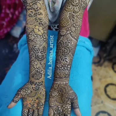 A classic example of full-arm bridal henna, featuring a dense mix of floral, paisley, and geometric patterns. The shading technique adds depth and dimension to the design.