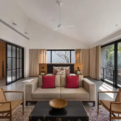 This spacious master bedroom in the Mango Orchard House features high, pitched ceilings and wall-to-wall glass doors that open to a private balcony. The room is large enough to accommodate a comfortable seating area, creating a versatile private retreat.