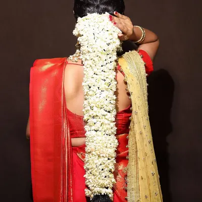 This is a classic South Indian bridal hairstyle, featuring a long, thick braid completely covered in fresh jasmine flowers, also known as a gajra or poola jada. It's a timeless and fragrant choice for a traditional wedding ceremony.