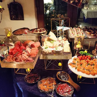 An elaborate cheese and charcuterie grazing table for an intimate gathering. The spread includes a variety of cured meats, artisanal cheeses, dips, and canapés, beautifully arranged with candelabras for a warm, inviting ambiance.