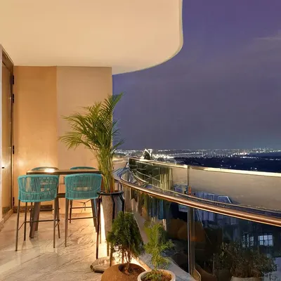 This curved balcony offers a stunning nighttime view of the city. We added a high-top table and bright teal chairs, creating a perfect spot for an evening drink or quiet contemplation.