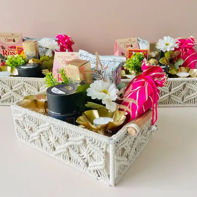 This beautiful macrame tray hamper is a very popular choice for Diwali. It's filled with sweets, a diya, and other festive items, creating an elegant gift.