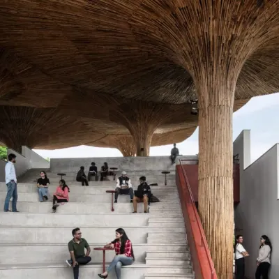 Students and faculty gather at the TAPMI Centre's amphitheater. This space is the heart of the project, designed to be a democratic forum for exchange, sheltered by an intricate canopy of bamboo that filters light like a forest.