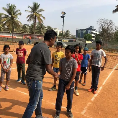 A handshake to congratulate Arjun on becoming 'Player of the Week'. Recognizing consistent effort in front of the group builds confidence and inspires everyone to push harder.