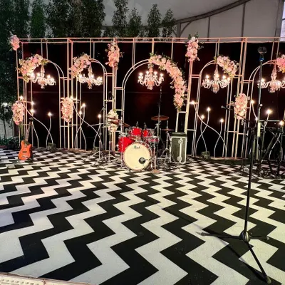 The complete stage setup for the 60th birthday bash. The design featured a striking chevron-patterned floor, elegant floral arrangements, and a full backline for the live band.