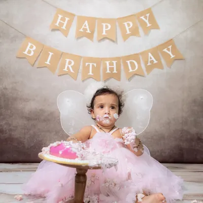 A little fairy in a pink dress having the best time during her cake smash session. The frosting on her face says it all!