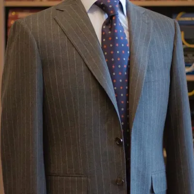 A grey pinstripe suit is a cornerstone of any professional wardrobe. This two-button suit, crafted from 130's count wool, offers a classic silhouette with the unmatched quality of a bespoke fit.