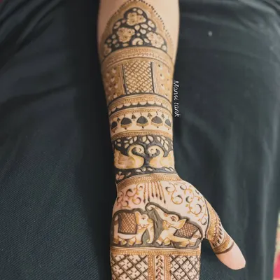 This forearm design is a beautiful showcase of traditional motifs. It features a pair of loving swans, majestic elephants, and an ornate dome pattern at the top.