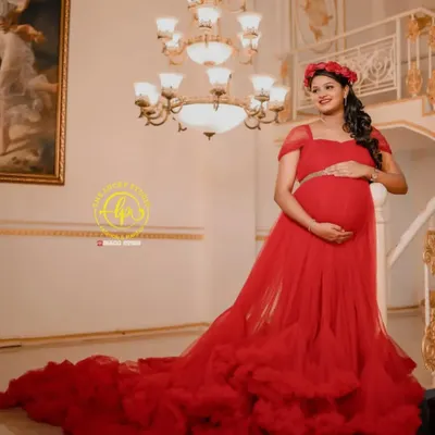 Feel like a queen in this stunning red ruffled trail gown, a perfect choice for a glamorous indoor maternity shoot. The floral headpiece adds a soft, romantic touch.