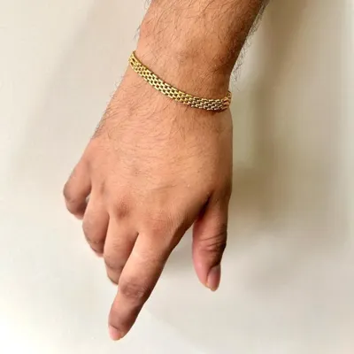 This handcrafted bracelet features an intricate, flexible weave of solid gold, creating a piece that is both visually interesting and exceptionally comfortable to wear. It’s a subtle expression of style and craftsmanship.