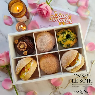 Here's an assortment box from my 'Cruel Summer' Valentine's menu. It shows the variety I offer, from filled doughnuts to doughnut sandwiches, with both sweet and savory options.