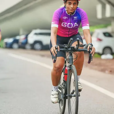 A powerful action portrait of a Goan cyclist. Her direct gaze and focused expression capture the mental toughness required for endurance sports. This is a perfect example of an on-location athlete portrait.