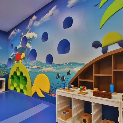 This ocean-themed classroom at Supaksha features a turtle-shaped climbing wall and custom low-height tables for hands-on activities. The entire space is designed to be an interactive learning habitat.