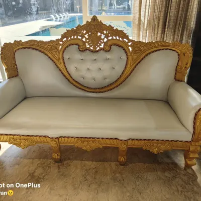 A close-up of our beautiful golden and white wedding sofa. This piece is a favorite for stage setups and adds a touch of royalty to any event. It is available for rent.