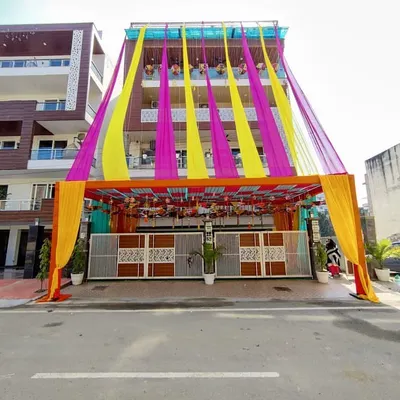 A full view of a multi-story house decorated for a wedding. I use long, flowing drapes in bright yellow and pink that run from the rooftop down to the entrance canopy, making a big visual impact.