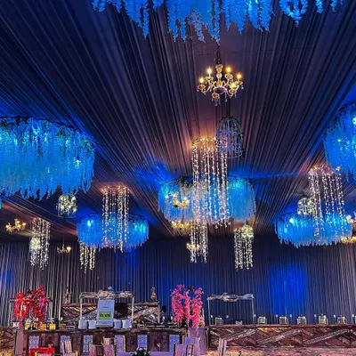 Lighting is key to creating atmosphere. Here, we used a combination of deep blue ambient light, classic chandeliers, and hanging crystal fixtures to create a magical, starry night effect inside the event tent.