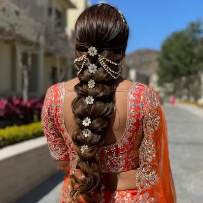 A close-up of a stunningly detailed bridal braid. I used floral accessories and a pearl hair chain to create a look that is both traditional and incredibly photogenic, perfect for a daytime wedding.