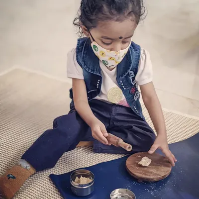 Practical life activities are the heart of our curriculum. Here, a child is using a small rolling pin and board to work with dough. These are not toys, but real, child-sized tools that help develop coordination, concentration, and a wonderful sense of accomplishment.