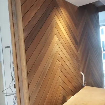 A stunning feature wall created with IPE wood planks arranged in a herringbone pattern. The natural variation in the wood grain adds warmth and texture, creating a sophisticated and timeless look.