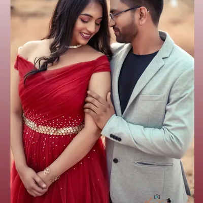 A tender moment between a stylish couple. Her off-shoulder red gown with a sparkling belt pairs beautifully with his light grey blazer for a modern pre-wedding look.