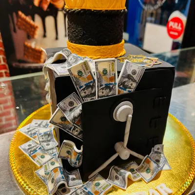 Celebrate a big win with this incredible money vault cake. The edible vault is overflowing with meticulously crafted fondant dollar bills, topped with a golden crown.