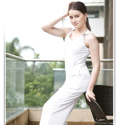 An international model in a white jumpsuit poses on a balcony, creating a clean, high-fashion look for a professional model portfolio or brand lookbook.