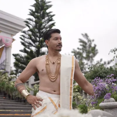 A groom with a regal presence. He is wearing a traditional multi-layered antique necklace, perfect for a South Indian muhurtham ceremony.