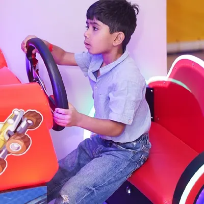 A young boy gets into the driver's seat of our "Happy Racing" arcade game, ready for a virtual race.