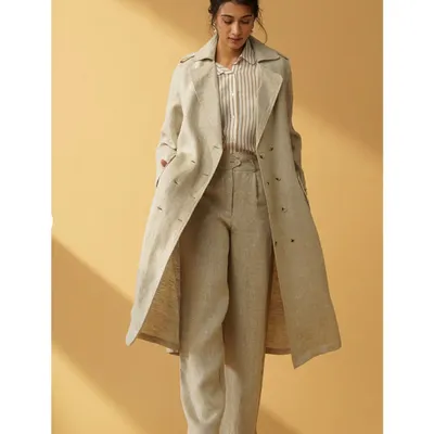 A full-length shot from a studio session for B77Life. I am wearing a modern trench coat and wide-leg trousers, showcasing a confident and sophisticated look for a contemporary fashion brand.