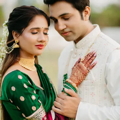 A serene and intimate portrait focusing on the bride's intricate mehendi and the groom's gentle touch. Dressed in traditional Maharashtrian attire, their closed eyes and soft smiles convey a deep sense of peace and love.