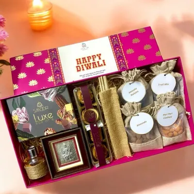 This is my 'Premium Affair' Diwali hamper, a truly luxurious curation. It includes Smoor luxe chocolates, a silver Lakshmi Ji frame for blessings, baklava, a lavender reed diffuser, and an assortment of gourmet nuts, all packed in a stunning designer box.