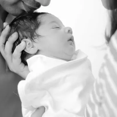 A tender black and white moment of a newborn being held by their parents. This style emphasizes emotion and connection.
