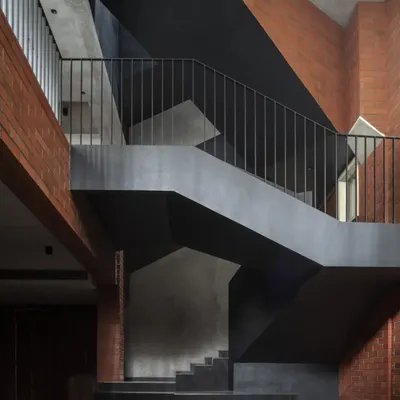The central staircase of the Brick House is a non-linear journey through the home. Its sharp, geometric forms in black pigmented plaster create a powerful contrast with the warmth of the exposed brick walls.