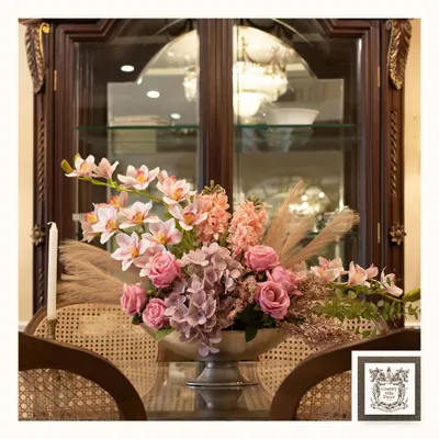 This elegant artificial floral arrangement, with its mix of pink roses, hydrangeas, and pampas grass, brings timeless beauty to this dining area. The flowers will never fade, providing a lasting centerpiece.
