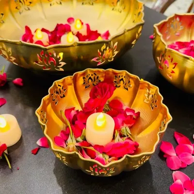A close-up of our lotus-cutwork urli bowls, handcrafted from metal with a gold finish. Filled with water, rose petals, and floating candles, they create a serene and beautiful centerpiece for Diwali and other festivities.