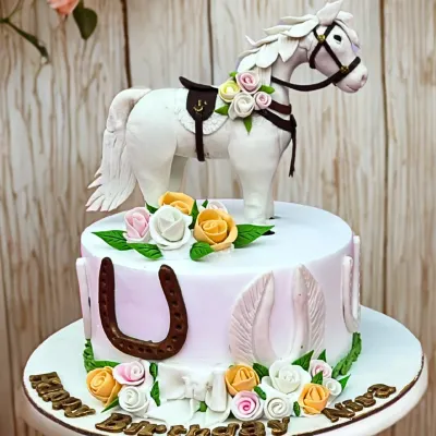 A stunning two-tier equestrian cake featuring a beautifully sculpted white horse, horseshoes, and a delicate arrangement of sugar roses.