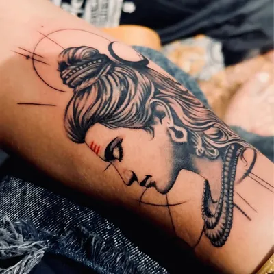A close-up of a Lord Shiva tattoo, showcasing the fine line work and dot-style shading. This modern artistic approach brings a divine symbol to life on the skin.