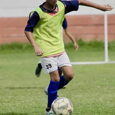 A young player focuses on his dribbling technique, maneuvering the ball with precision. This fundamental skill is the building block for every great player.