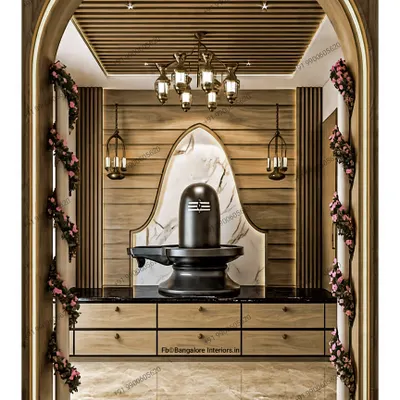 This stunning pooja space features a magnificent black Shivling set against a white marble arch and a wood-paneled backdrop. The traditional hanging lamps and floral decorations add to the divine atmosphere.