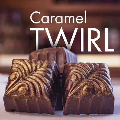 Our Caramel Twirl pralines show curved moulded shells and gold-coloured swirls in this close-up from the Belgian Praline range.