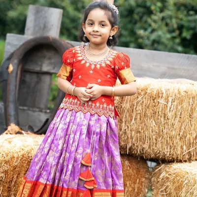 This little one looks absolutely radiant in her custom Kanchi Pattu lehenga. The vibrant red and purple combination is perfect for festive occasions.